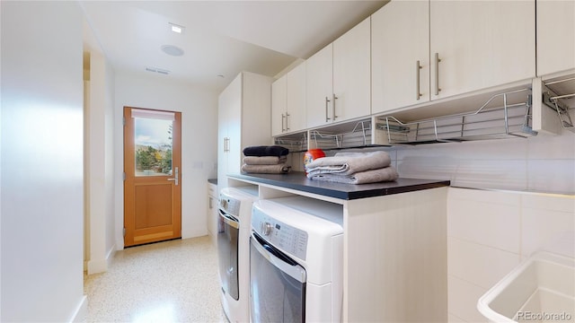 washroom with sink, washing machine and dryer, and cabinets