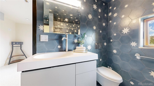 bathroom featuring vanity, toilet, and tile walls