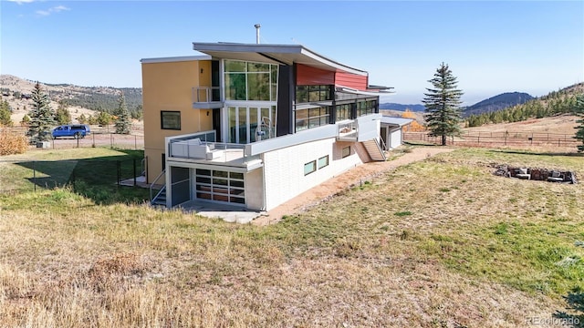 back of property with a mountain view, a lawn, and a sunroom