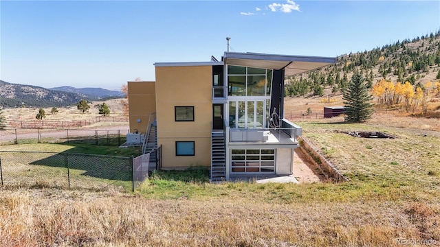 back of property featuring a rural view, a mountain view, and a sunroom