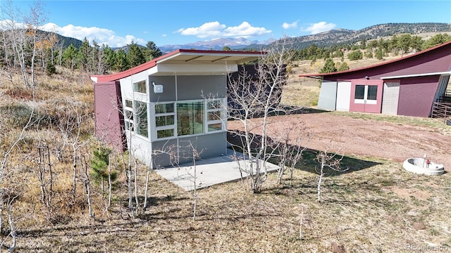 view of side of home with a mountain view and an outbuilding