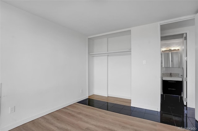 unfurnished bedroom featuring a closet, baseboards, and wood finished floors