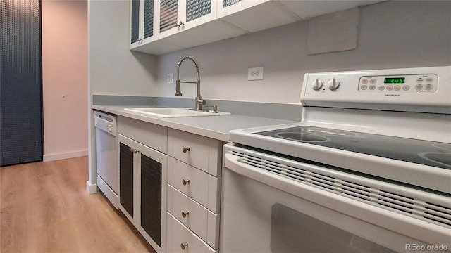 kitchen with a sink, light countertops, light wood-style floors, dishwasher, and white electric range