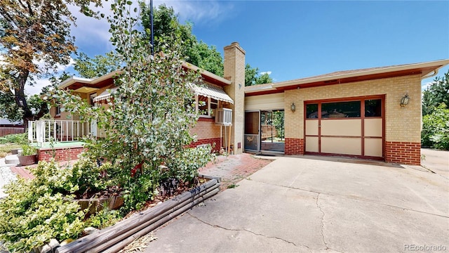 4420 Teller St, Wheat Ridge, CO 80033 - view of front facade featuring brick siding, a chimney, concrete driveway, and an attached garage