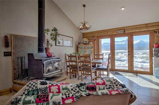 dining area featuring a mountain view, a wood stove, high vaulted ceiling, a notable chandelier, and light tile patterned flooring