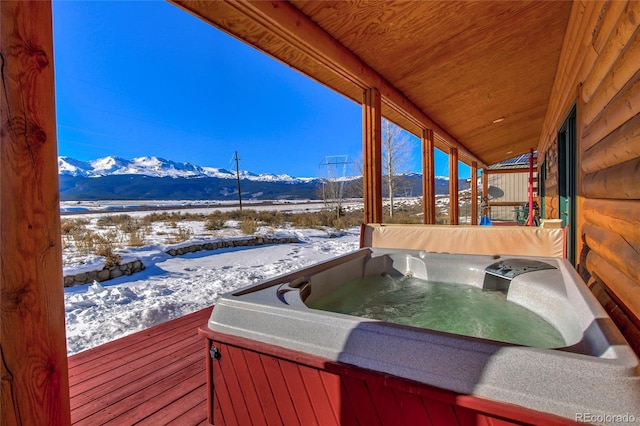 snow covered deck with a mountain view and a hot tub