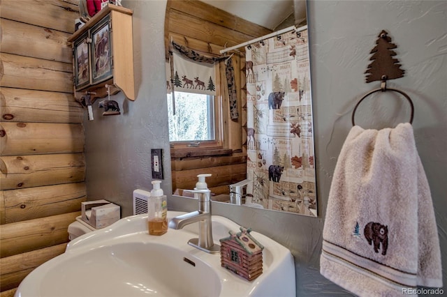 bathroom featuring log walls, a shower with curtain, and sink