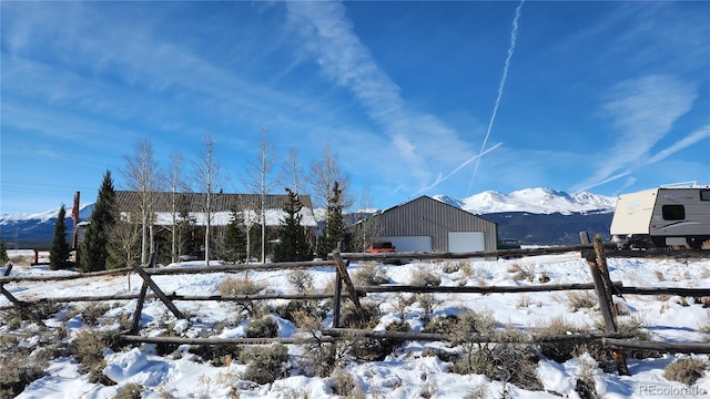 yard layered in snow featuring a mountain view, an outdoor structure, and a garage