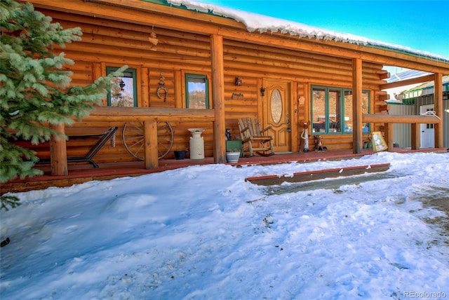 snow covered property entrance with covered porch