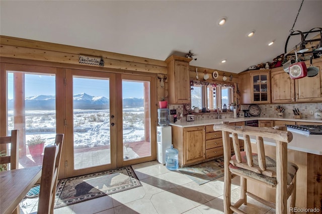 kitchen featuring french doors, a mountain view, lofted ceiling, decorative backsplash, and light tile patterned flooring