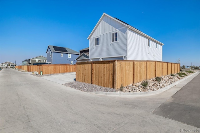 view of side of home featuring board and batten siding and fence