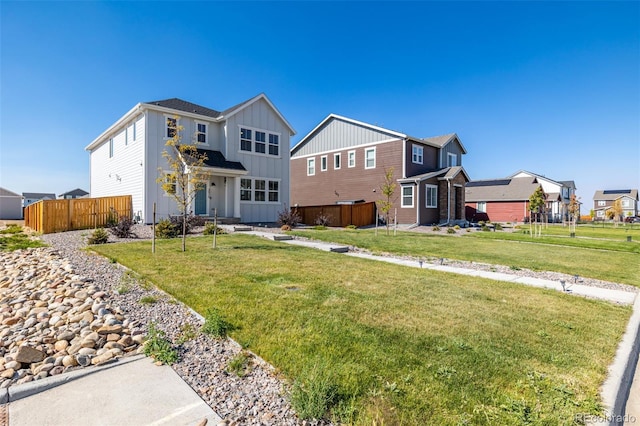 view of front of home featuring a residential view, board and batten siding, a front lawn, and fence