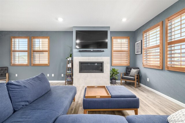 living area with recessed lighting, wood finished floors, baseboards, and a tile fireplace