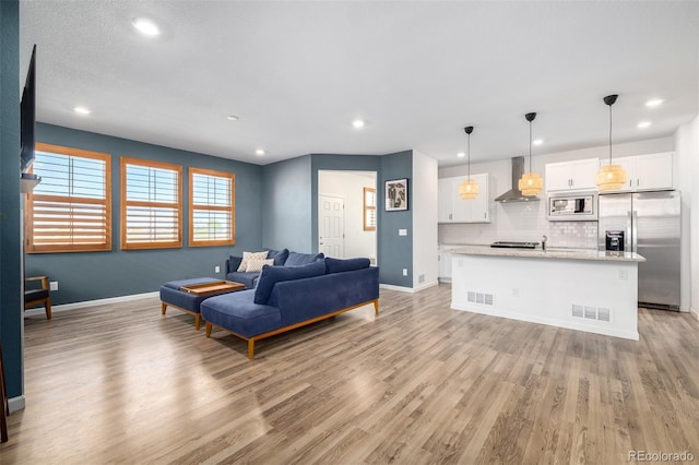 living room featuring visible vents, baseboards, and light wood finished floors