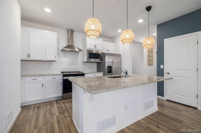 kitchen with visible vents, a sink, white cabinetry, stainless steel appliances, and wall chimney exhaust hood