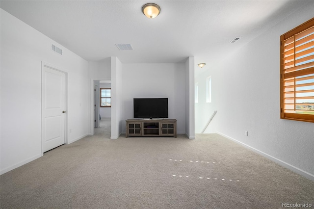 unfurnished living room with baseboards, visible vents, and carpet floors