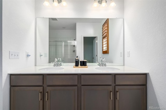 bathroom featuring double vanity, visible vents, a shower stall, and a sink