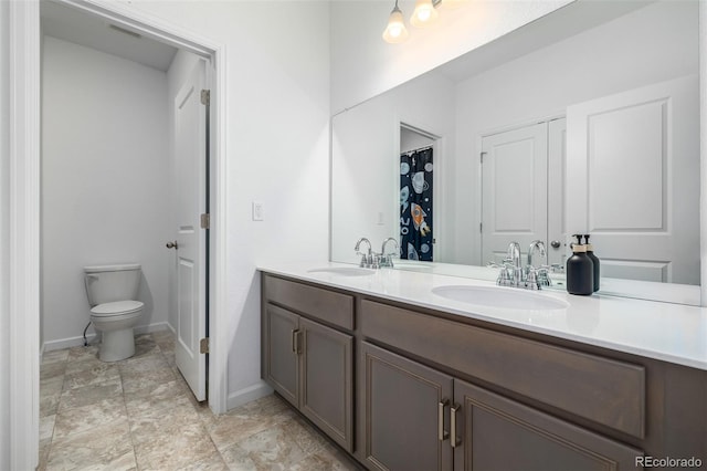 full bathroom with double vanity, toilet, and a sink