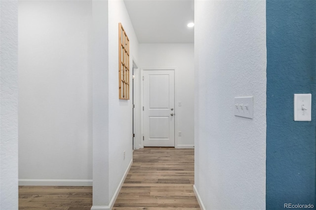 corridor featuring wood finished floors and baseboards