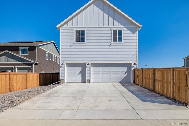 view of front of house with an attached garage, fence, board and batten siding, and driveway