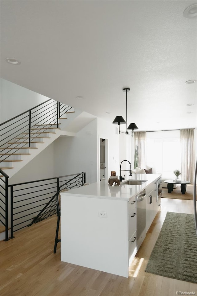 kitchen featuring a sink, white cabinetry, light wood-type flooring, dishwasher, and modern cabinets