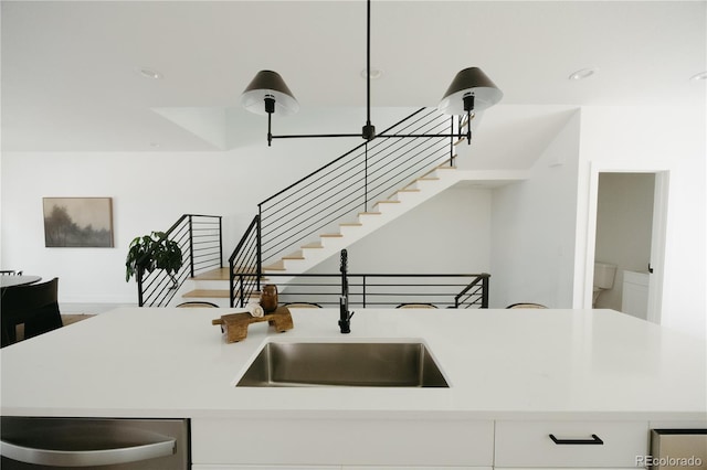 kitchen featuring white cabinets, light countertops, a sink, and dishwasher