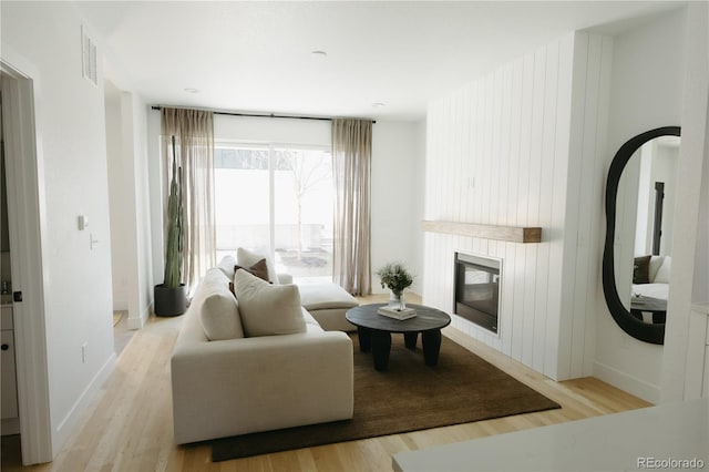 living room with light wood-style floors, baseboards, a fireplace, and visible vents