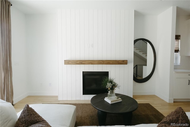 living room featuring light wood-type flooring, a fireplace, and baseboards