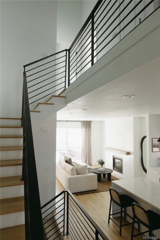 staircase with wood finished floors and a glass covered fireplace