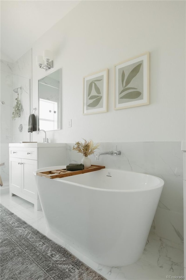 bathroom featuring marble finish floor, a soaking tub, and vanity