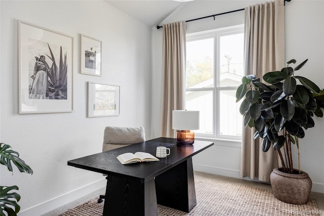 home office with vaulted ceiling, plenty of natural light, light carpet, and baseboards