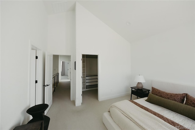 bedroom with a closet, visible vents, light carpet, high vaulted ceiling, and baseboards