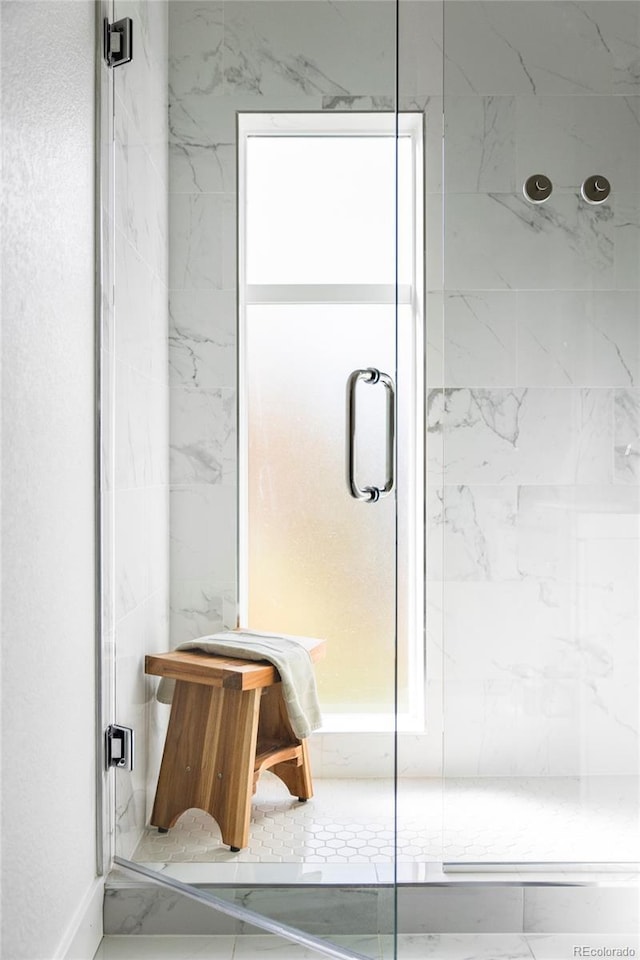 full bathroom with a marble finish shower and a wealth of natural light