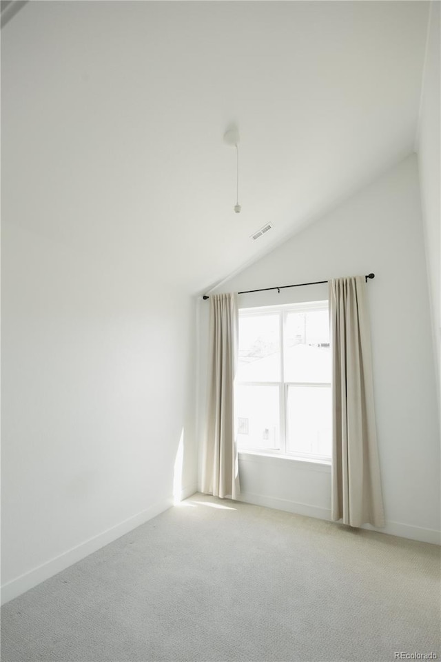 empty room featuring lofted ceiling, baseboards, visible vents, and carpet flooring