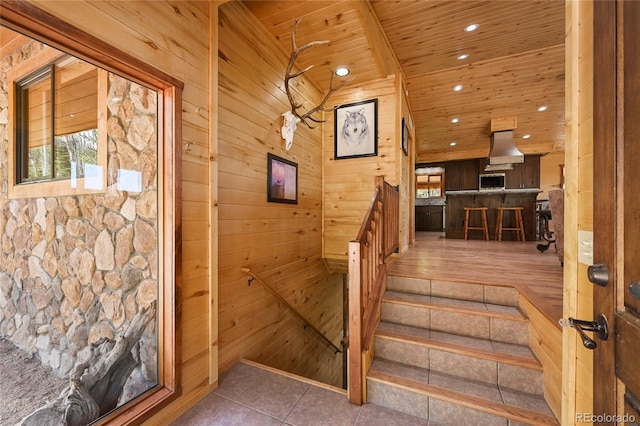 stairs with wood walls, wooden ceiling, tile patterned floors, and recessed lighting