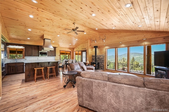 living area featuring light wood-type flooring, wooden ceiling, a wood stove, and recessed lighting