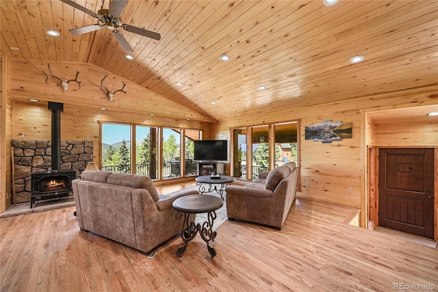 living area with light wood-style flooring, a wood stove, wooden walls, high vaulted ceiling, and wooden ceiling