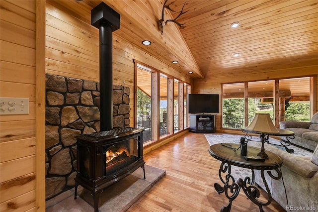 living room with wooden ceiling, wood walls, vaulted ceiling, light wood-type flooring, and a wood stove