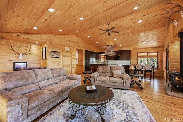 living area featuring vaulted ceiling, a wood stove, wooden ceiling, and wood walls