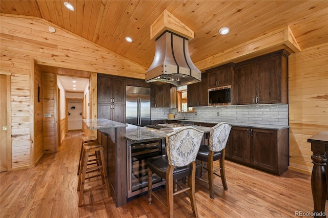 kitchen featuring lofted ceiling, wood ceiling, a breakfast bar, stainless steel appliances, and wood walls