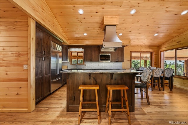 kitchen with wood ceiling, range hood, stainless steel appliances, and a kitchen breakfast bar