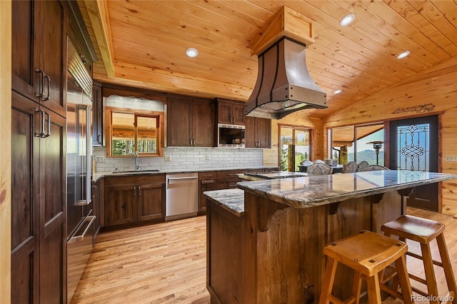 kitchen featuring wooden ceiling, stainless steel appliances, dark stone counters, a kitchen bar, and custom range hood