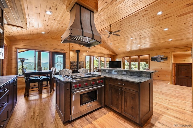 kitchen with a wood stove, wooden walls, premium range, and custom range hood