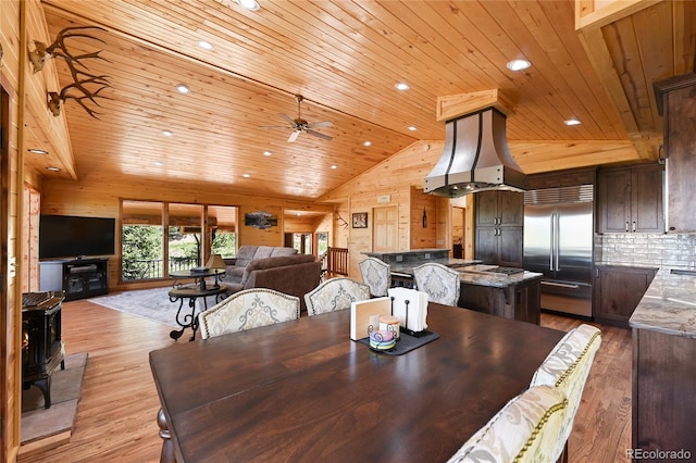 dining area with a wood stove, wood walls, and light wood finished floors