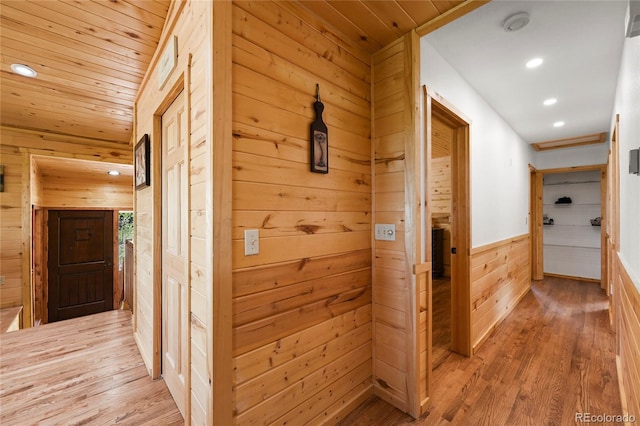 hallway featuring wooden ceiling, light wood-style flooring, and wooden walls