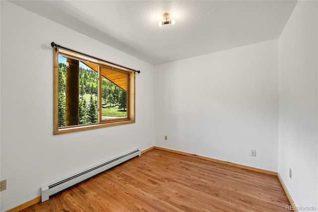 spare room with a baseboard heating unit, light wood-style flooring, and baseboards