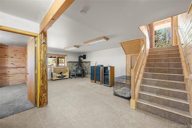 below grade area featuring a wood stove, stairs, and wooden walls