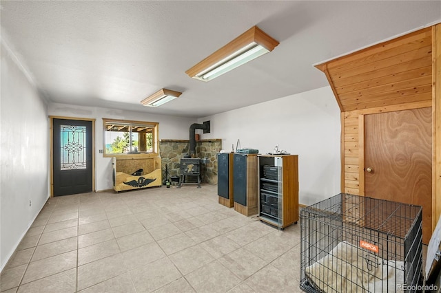 interior space with a wood stove and light tile patterned floors