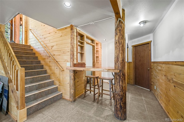 staircase with a wainscoted wall, wood walls, and tile patterned floors