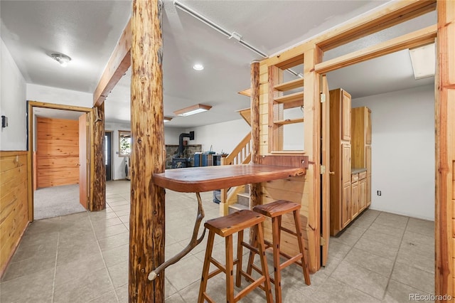 dining space with wood walls, stairway, and a wainscoted wall